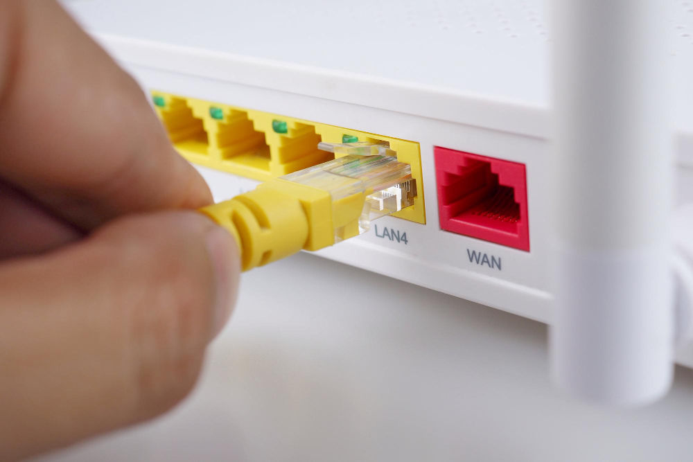 Picture of a person plugging in a network cable to a modem.